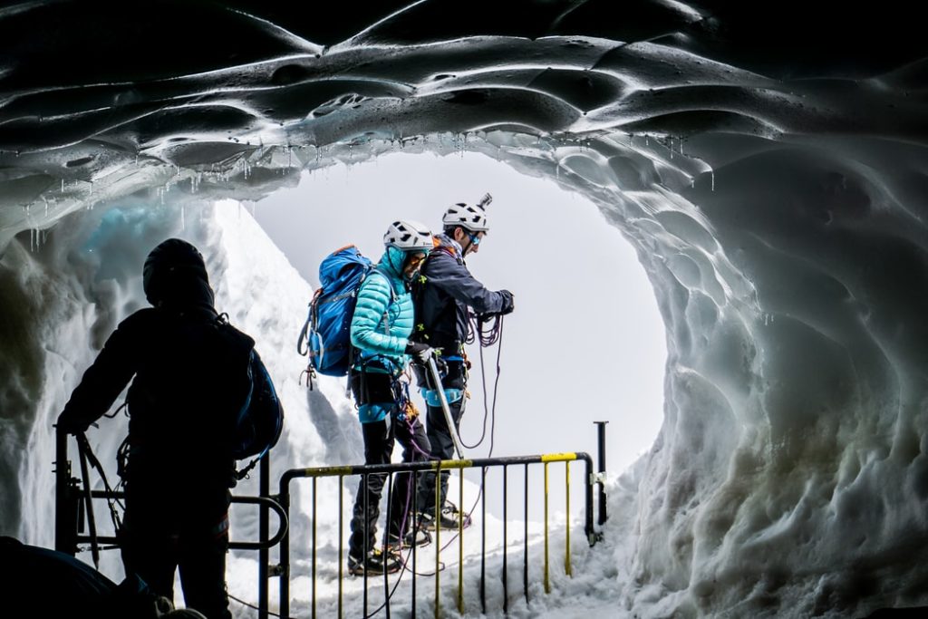 Ледовые занятие альпинизм. Экстремальные условия жизни в городе. Picture of people Walking in an Ice Cave.